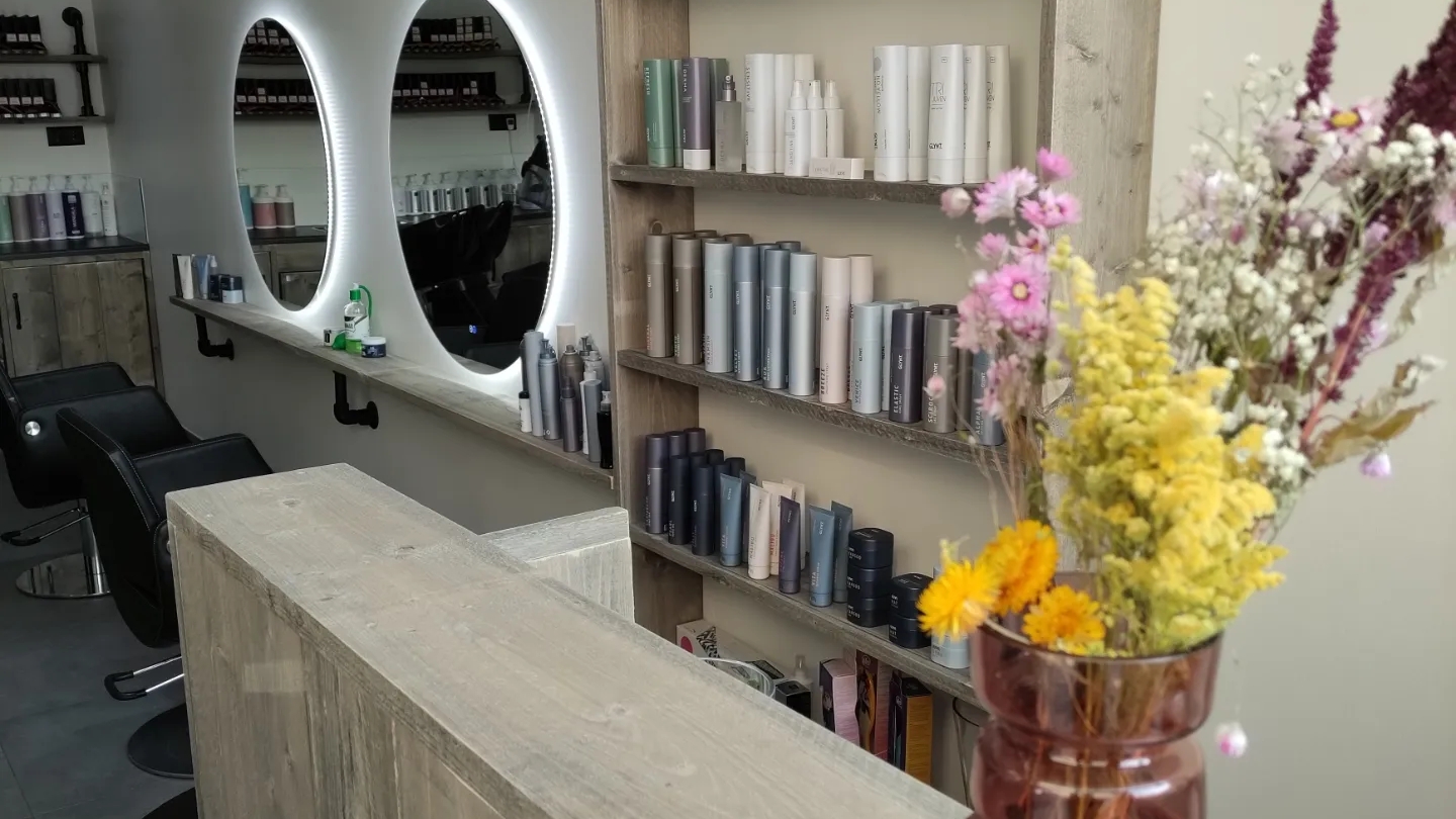 De salon: houten balie, ronde verlichte spiegels, schappen met Glynt producten en droogbloemen