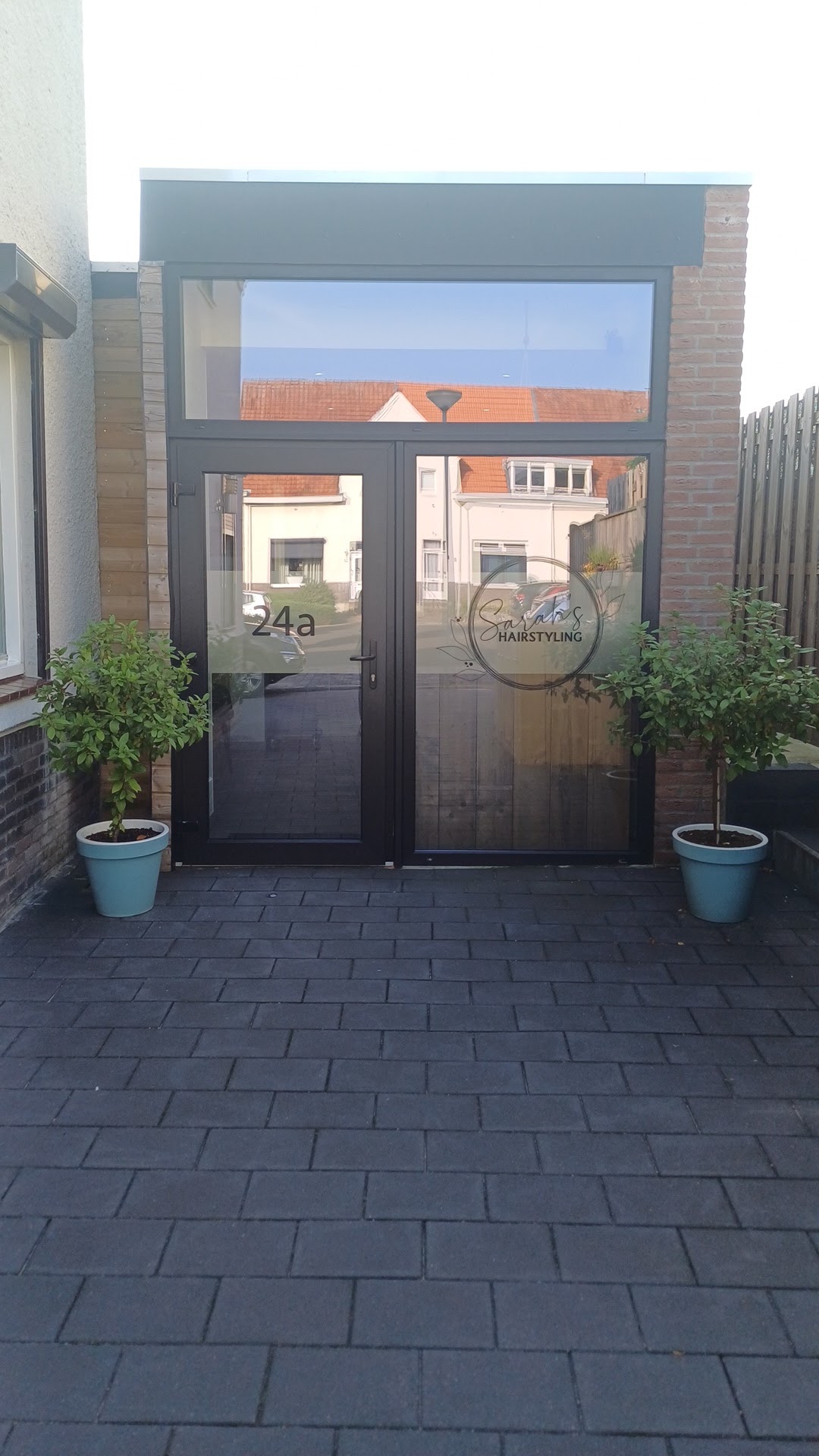 De ingang van Sarah's Hairstyling aan de Schutterstraat 24a, met twee plantenbakken